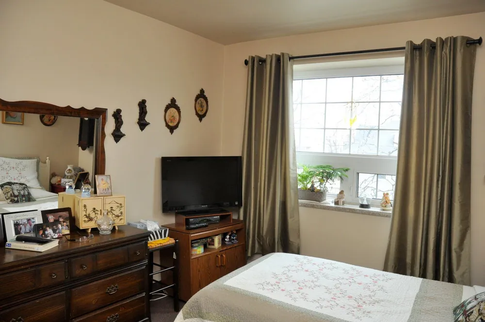 Suite bedroom with dresser and television, furnished with a resident's own belongings